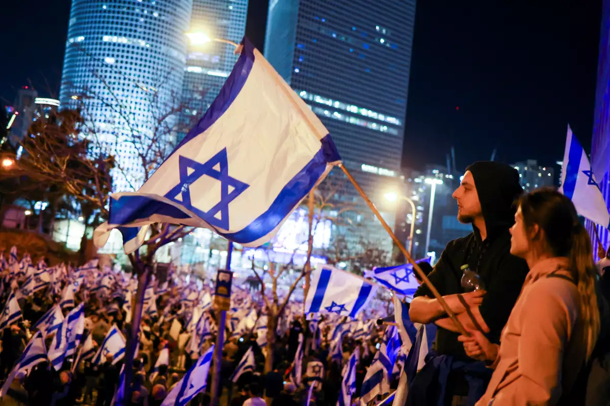 La gente sostiene banderas israelíes durante una manifestación mientras el gobierno de coalición nacionalista del primer ministro israelí, Benjamin Netanyahu, presiona con su polémica reforma judicial, en Tel Aviv, Israel, el 11 de marzo de 2023.