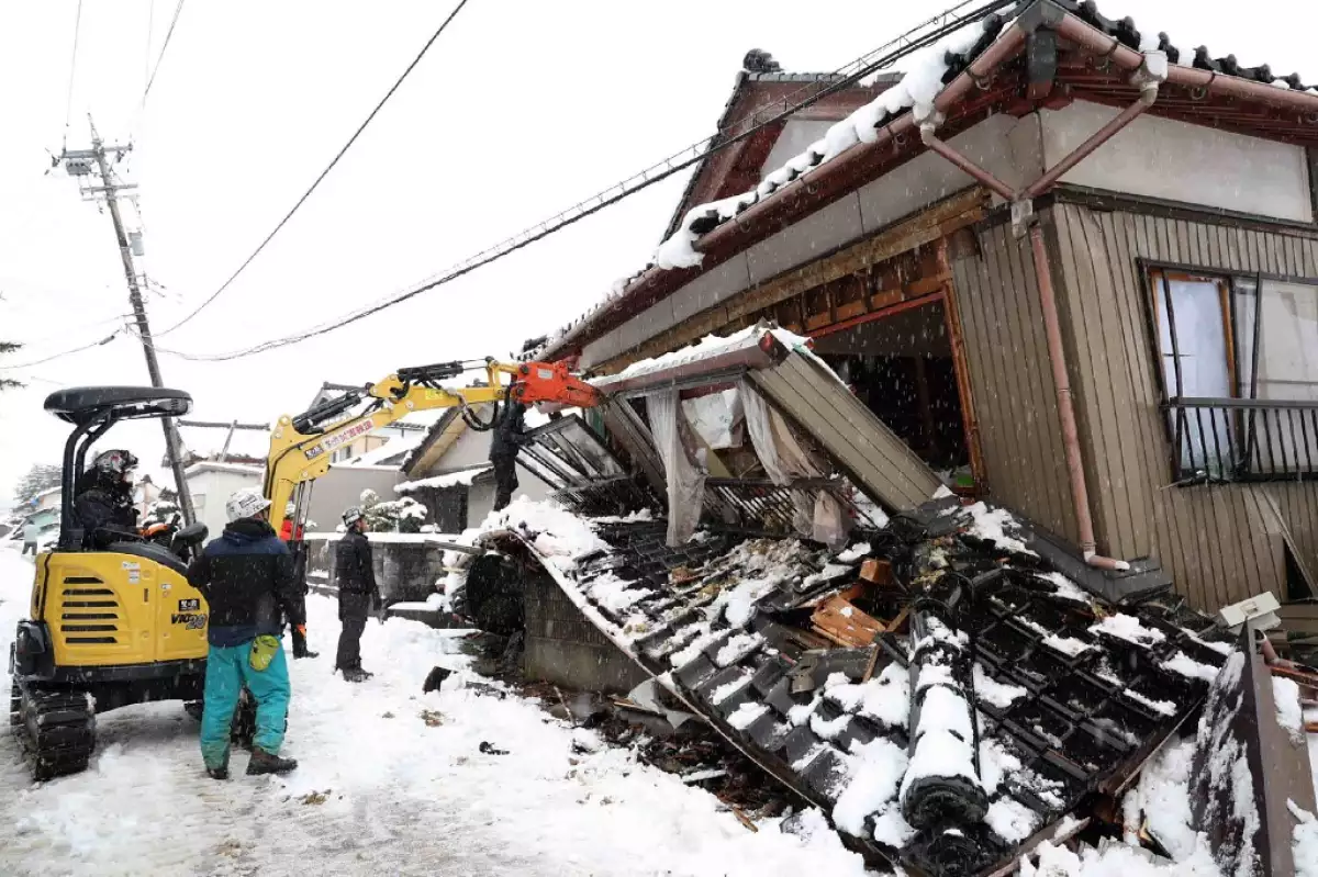 Esta foto tomada el 8 de enero de 2024 muestra a voluntarios demoliendo una casa parcialmente derrumbada porque el propietario estaba preocupado de que pudiera lesionar a los transeúntes en la ciudad de Suzu, prefectura de Ishikawa, una semana después de que un gran terremoto de magnitud 7,5 golpeara la región de Noto en la prefectura de Ishikawa el día de Año Nuevo.