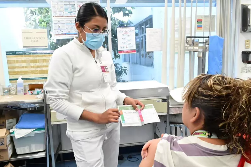 Una enfermera muestra la cartilla de vacunación a una paciente en México