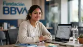 Una mujer joven frente a su computadora realizando su solicitud para la beca de BBVA.
