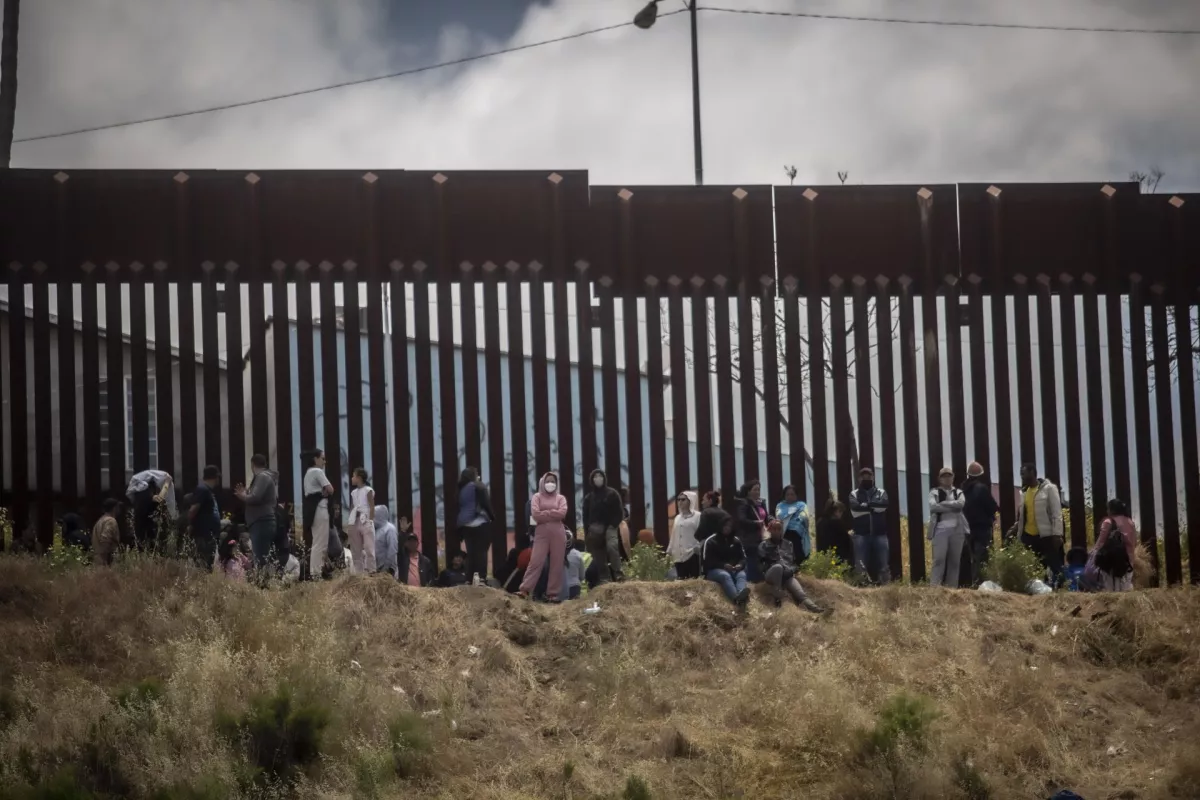 Migrantes en el muro fronterizo entre Estados Unidos y México.
