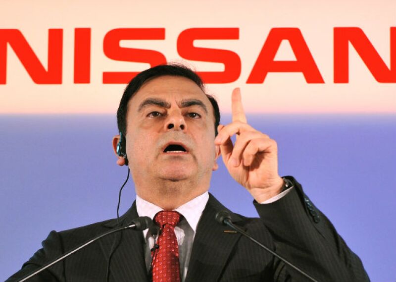 Carlos Ghosn frente a logo de Nissan