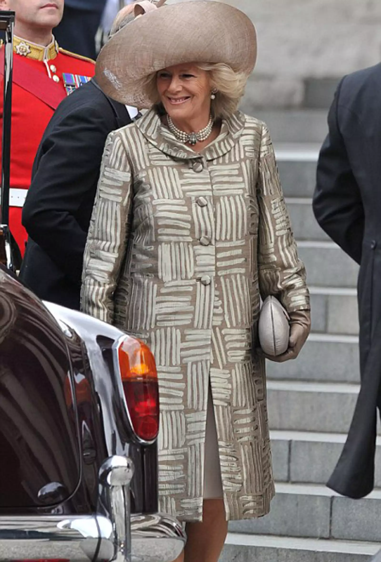 La duquesa de Cornualles, Camila Parker le dio un giro vanguardista a su look con una gabardina con motivos gráficos con terminados metálicos del creativo Bruce Oldfield. A su vez destacó su atuendo con un sombrero de Philip Treacy.
