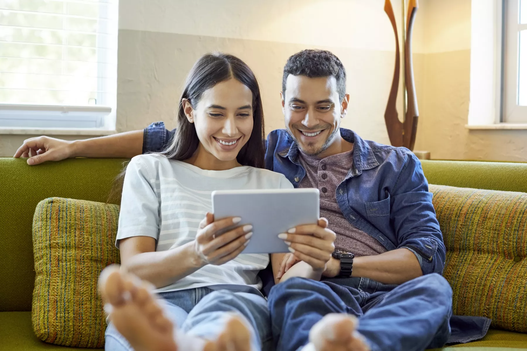 Smiling young couple using digital tablet at home