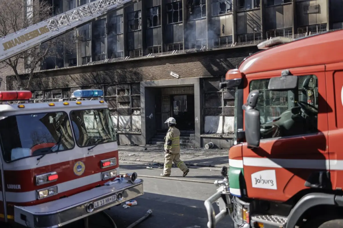 Un bombero sudafricano pasa junto a los camiones de bomberos en el lugar de un incendio en Johannesburgo el 31 de agosto de 2023. Más de 60 personas han muerto en un incendio que envolvió un edificio de cinco pisos en el centro de Johannesburgo el 31 de agosto de 2023, dijeron los servicios de emergencia de la ciudad sudafricana.