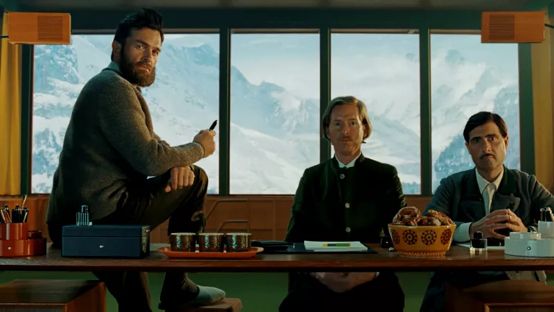 tres hombres ante un escritorio con plumas estilográficas y papeles, al fondo se observa el Mont Blanc.