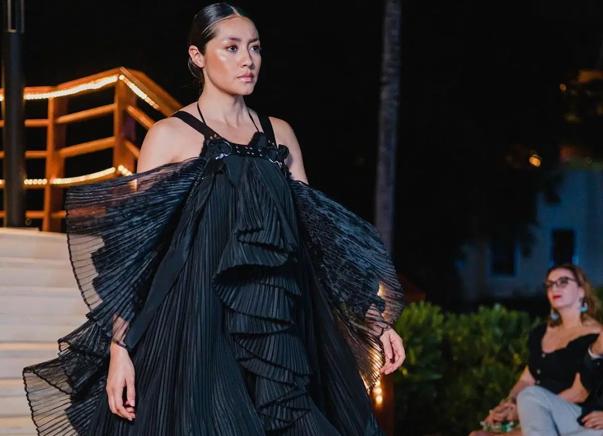 Mujer modelando con un vestido negro de Guillermo Jester. 