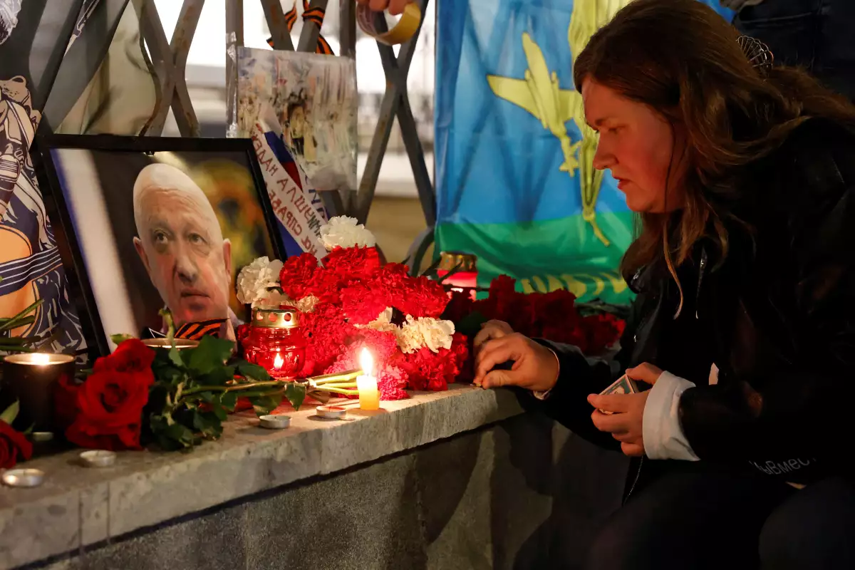 Una mujer enciende una vela frente a un retrato del jefe mercenario de Wagner, Yevgeny Prigozhin, en un monumento improvisado en Moscú, Rusia, el 24 de agosto de 2023.