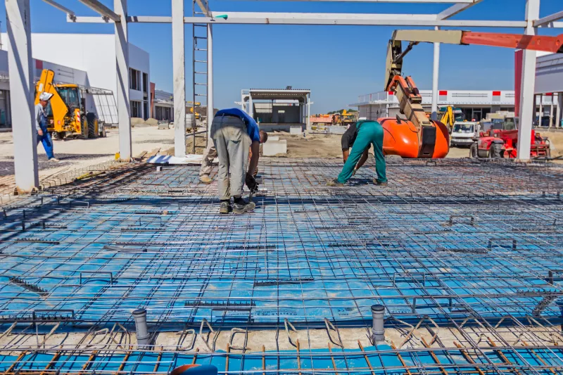 Workers are installing reinforcement mesh manually.