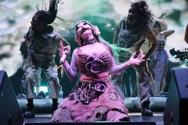 Foto de Melanie Martínez durante un concierto, vestida de color rosa y una máscara.