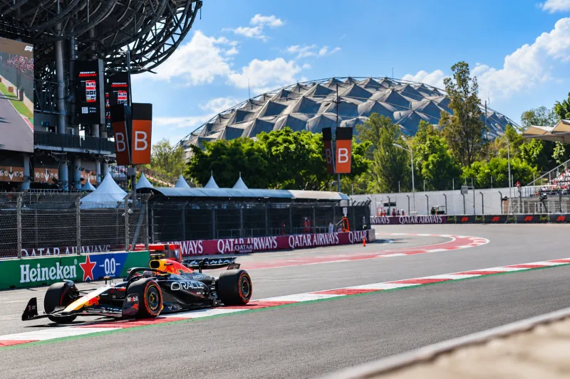 Auto de Fórmula 1 de Red Bull en una curva del Autódromo Hermanos Rodríguez, con el estadio y las gradas al fondo.