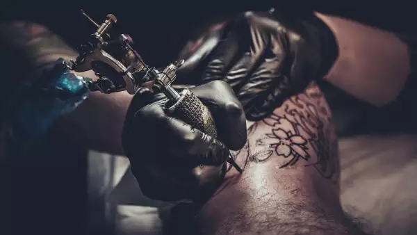 Tattoo master making tattoo on customer's leg