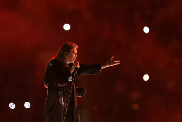 Foo de Ozzy Osbourne en un concierto de Black Sabbath en 2022 con la mano extendida izquierda hacia el público y el micrófono sostenido en la mano derecha.