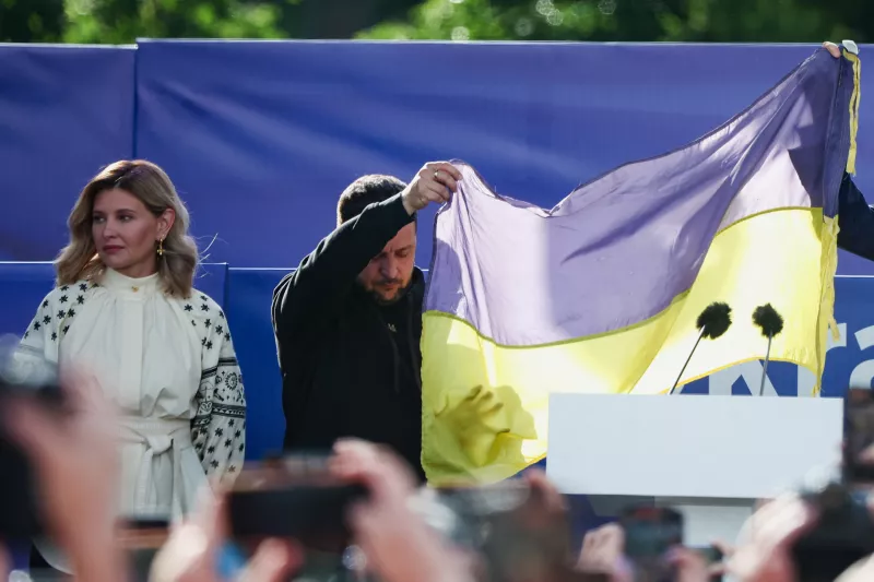 El presidente ucraniano Volodymyr Zelenskiy sostiene una bandera junto a su esposa Olena Zelenska mientras asisten a una ceremonia durante la cual los activistas entregan una bandera ucraniana de la primera línea de la guerra con Rusia, al margen de una cumbre de líderes de la OTAN en Vilnius, Lituania, el 11 de julio de 2023.