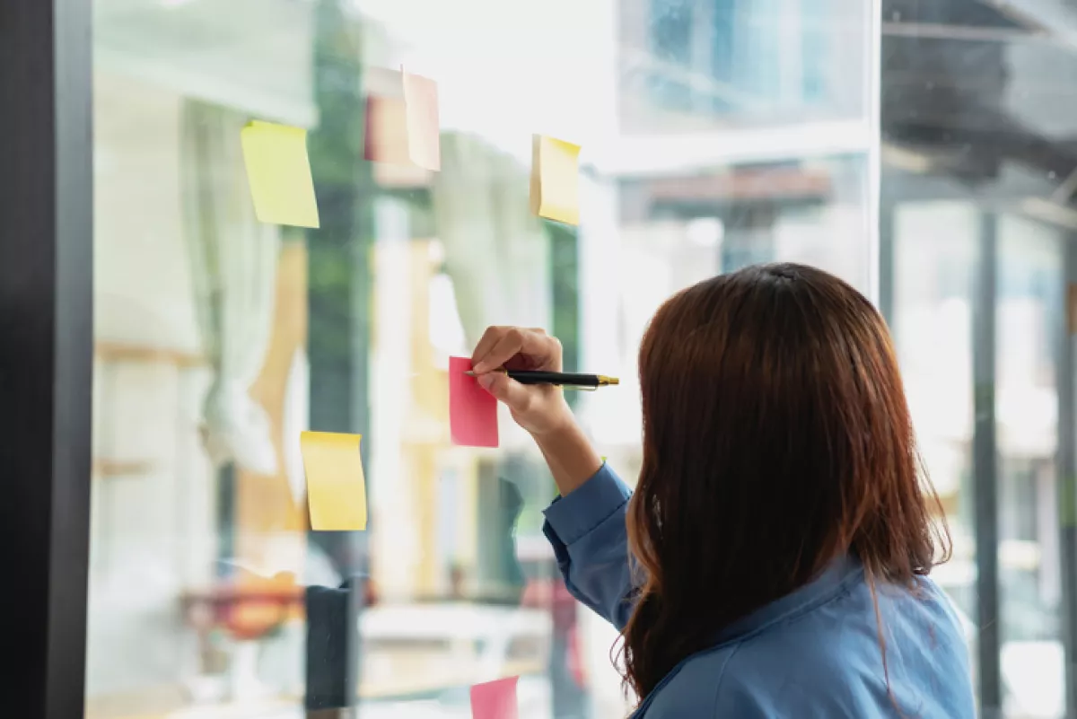 A female employee writes on a colorful notepad. 