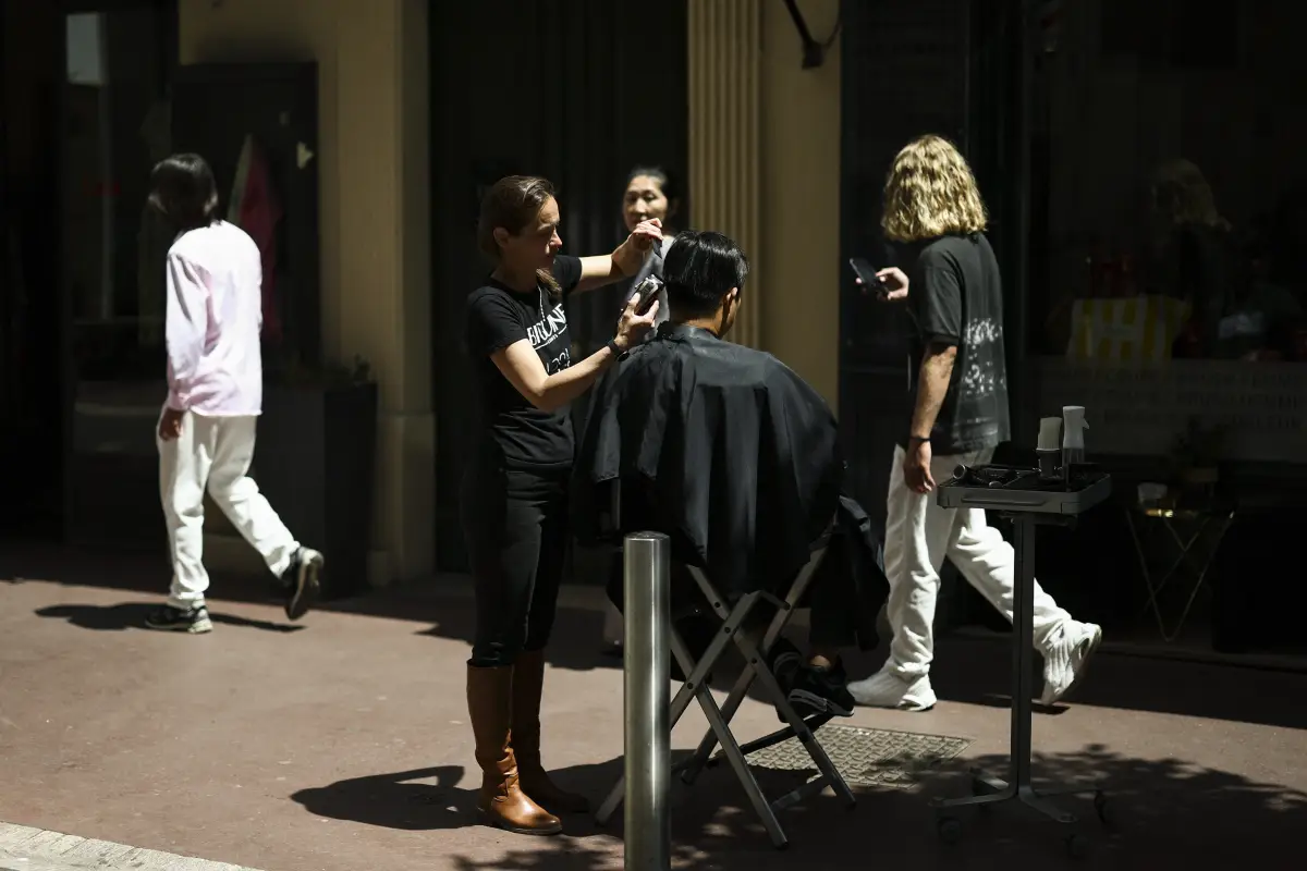 Una peluquera trabaja en el corte de pelo de un cliente en la calle debido a la falta de luz en su peluquería, después de un gran corte de electricidad, durante el 78o Festival de Cine de Cannes en Cannes, Francia, el 24 de mayo de 2025.