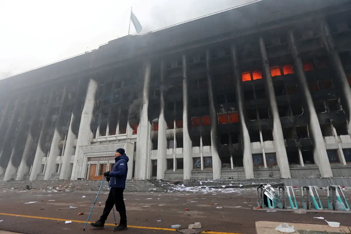 Un hombre está parado frente al ayuntamiento de Almaty, Kazajistán, que fue incendidado un día antes por manifestantes. 