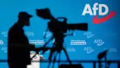 Un camarógrafo hace una silueta contra una pared con el logotipo de la AfD durante un congreso del partido ultraderechista alemán Alternativa para Alemania (AfD - Alternative fuer Deutschland) en Dresde, este de Alemania, el 11 de abril de 2021. 