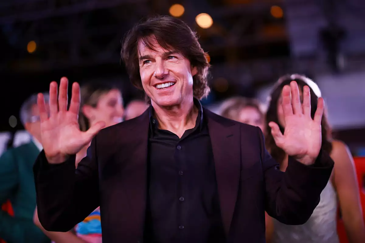 Foto de Tom Cruise sonriendo y con las manos al frente saludando a sus fans en la CDMX en la alfombra roja de Misión Imposible, en mayo de 2025.