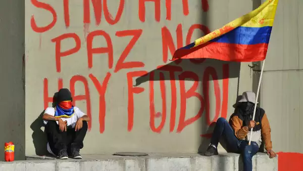 Los manifestantes se sientan junto a un grafiti que dice "Si no hay paz, no hay fútbol" en una pared del Estadio Campin mientras protestan contra Colombia, que alberga el torneo de fútbol de la Copa América durante una huelga nacional el 19 de mayo de 2021 en Bogotá, Colombia, el 19 de mayo de 2021 en Bogotá, Colombia.