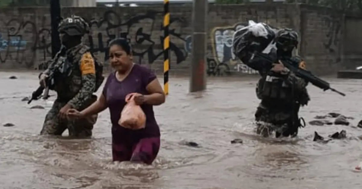 Dos integrantes del ejército ayudan a una mujer en medio de inundaciones.jpg