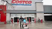 Clientes caminando con un carrito lleno fuera de Costco.