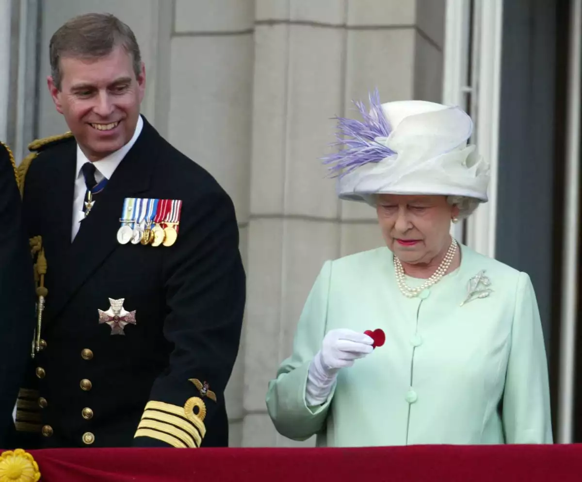 La reina Isabel II sostiene una amapola caída de una bomba Lancaster mientras está de pie junto al príncipe Andrés en el balcón del Palacio de Buckingham durante las celebraciones que marcan el final de la Segunda Guerra Mundial en Londres el 10 de julio de 2005.