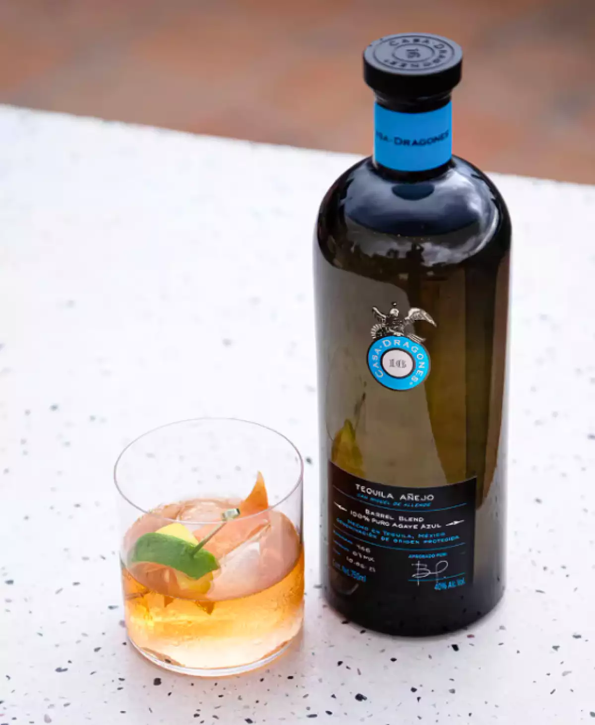 foto de la botella de Tequila Casa Dragones Añejo junto a un vaso con un drink preparado