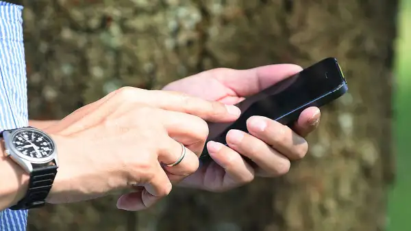 Una persona donde solo se ve su mano que está sosteniendo un teléfono para llamar