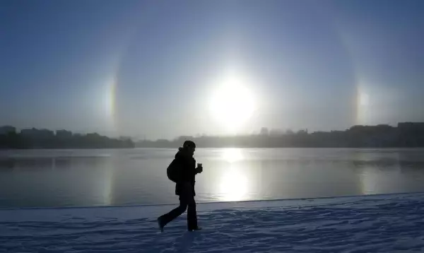 Una mujer pasea a orillas del lago Malaren con el fenómeno atmosférico Parhelio visto al fondo