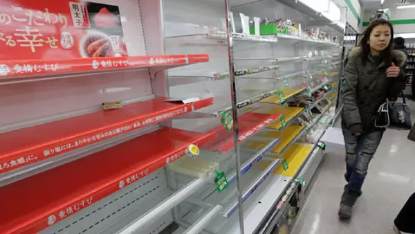 Una mujer busca provisiones en una tienda de Tokio, a pesar de que las tiendas muestran muy poca comida y agua.