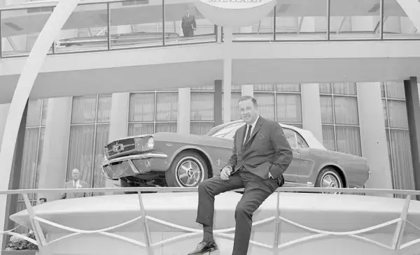 Henry Ford II sentado junto al mítico Mustang 1964 que logró catapultar a la marca en el segmento deportivo.