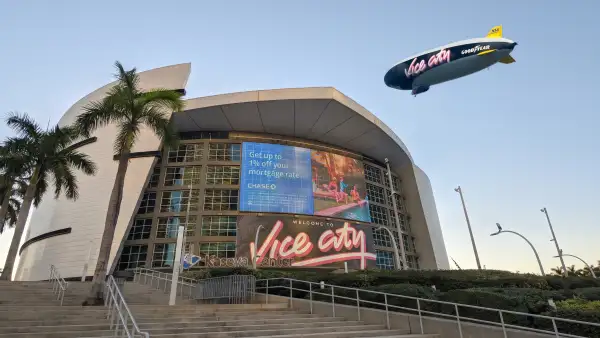 Integración generada por IA de dos fotografías reales, una del Kaseya Center y otra de un dirigible que sobrevuela la ciudad de Miami.