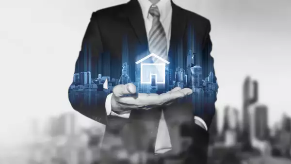 Businessman holding modern buildings hologram, and home icon. Real estate business, building technology and smart home concept