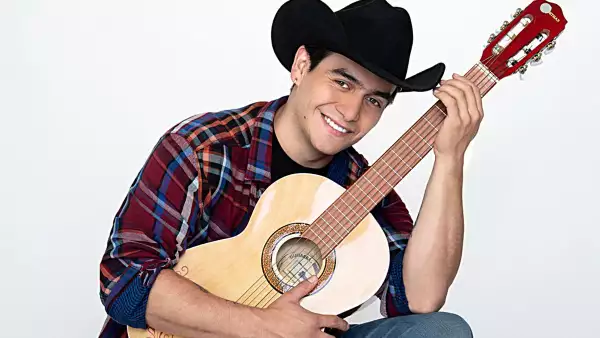 El cantante Julián Figueroa sostiene una guitarra y sonríe a la cámara