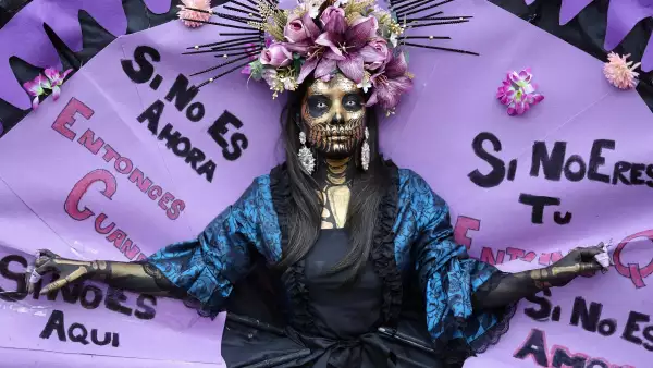 Una mujer desfila con una lectura escrita "Si no ahora, ¿cuándo? Si no es aquí, ¿dónde? Si no eres tú, ¿quién? Si no con amor y rebelión, ¿cómo? Durante una manifestación con motivo del Día Internacional de la Mujer en Madrid el 8 de marzo de 2026