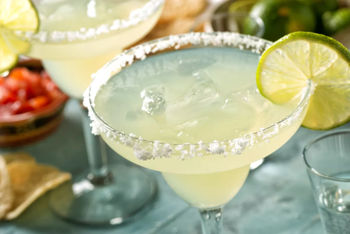 Margarita en copa de coctel con sal y limón sobre una mesa verde.