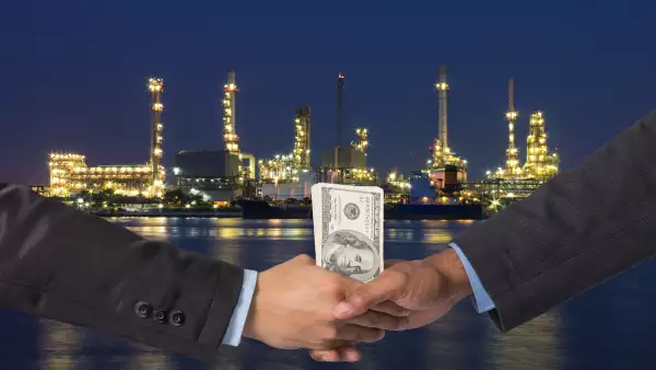 Hand shake between a businessman with dollar money on Petrochemi