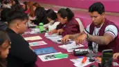 Seis mujeres y tres hombres sentados alrededor de una mesa color vino, en medio hay papeles, folders y plumas.jpg