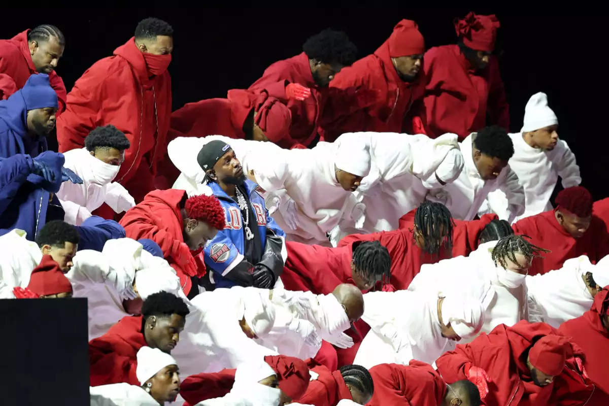 Foto de Kendrick Lamar durante el show de Medio Tiempo del Super Bowl LIX, parado con las manos al frente y rodeado de bailarines vestidos de blanco, rojo y azul.