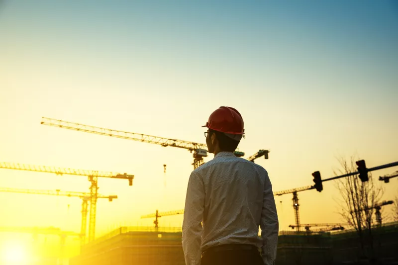 Engineer with crane background at sunset