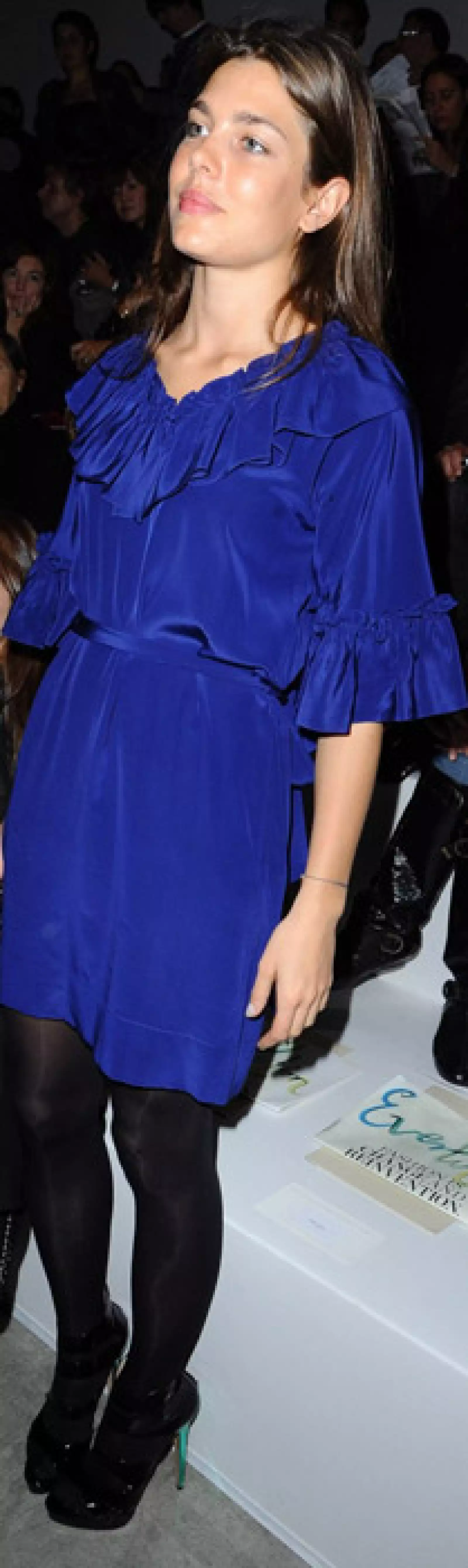 Vestido azul rey con holanes en cuello y mangas, medias y pumps de charol negros.