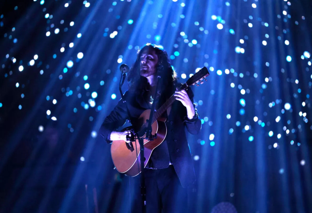 Foto de Hozier en concierto con un juego de luces que parecen luciérnagas.
