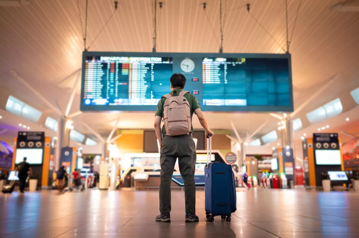 Male tourist looking at arrival and departure board at Kuala Lumpur International Airport