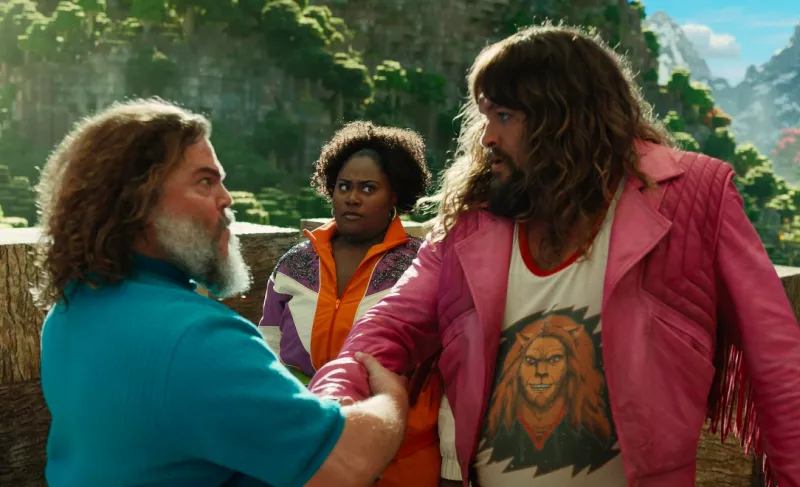 Foto de una escena de 'Una película de Minecraft' con Jack Black y Jason Momoa viéndose de frente con expresión de luchar y detrás los observa extrañada Danielle Brooks.
