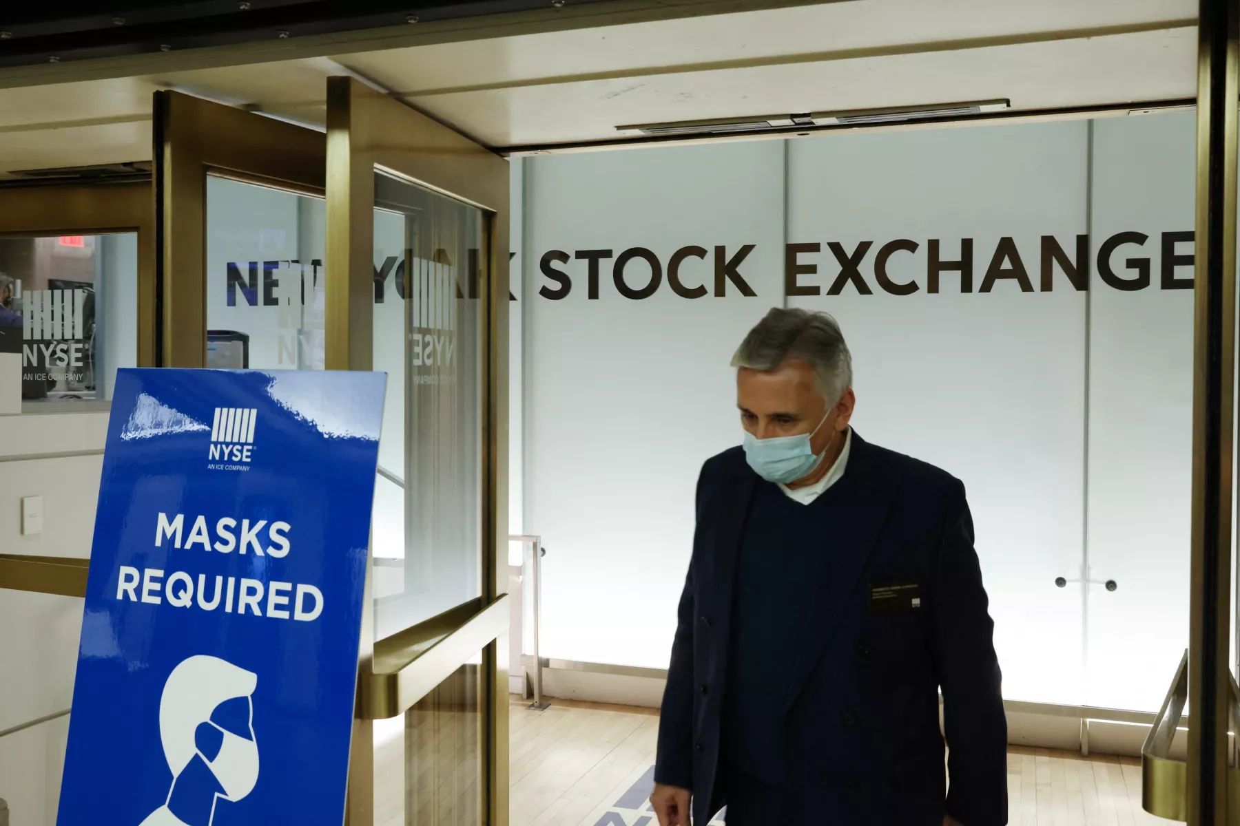 Signo que pide a las personas que usen cubebocas es visto en la Bolsa de Valores de Nueva York.
