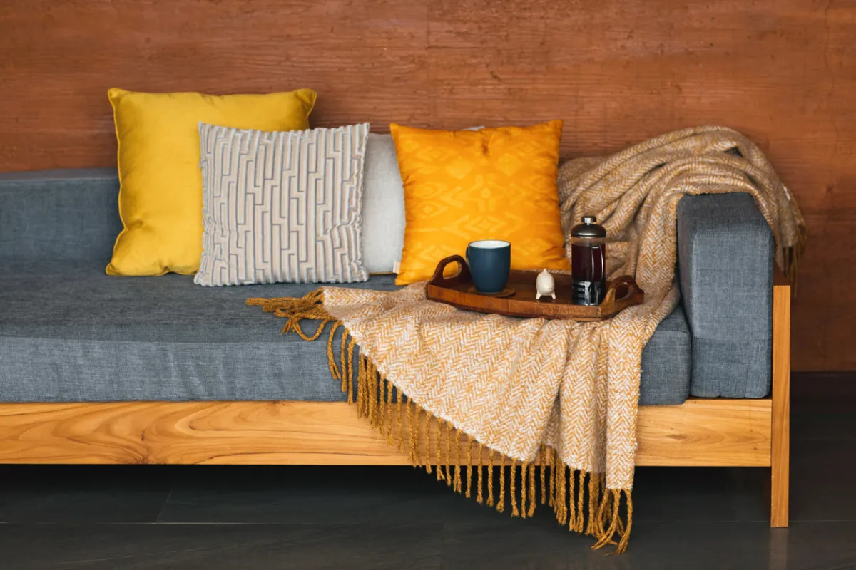 Serving tray with tea on gray sofa.
