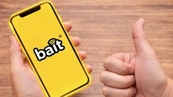 Una persona sosteniendo un teléfono con fondo amarillo y con el logo de Bait, el OMV de Walmart. 