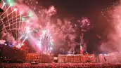 Fuegos artificiales en verde, blancoo y rojo sobre el zócalo de la CDMX con la bandera de México al fondo durante el grito de independencia.