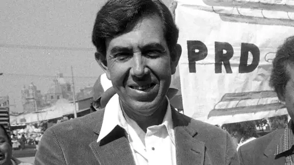 Foto de Cuauhtémoc Cárdenas de joven, con camisa blanca y saco oscuro, durante un acto político del PRD.